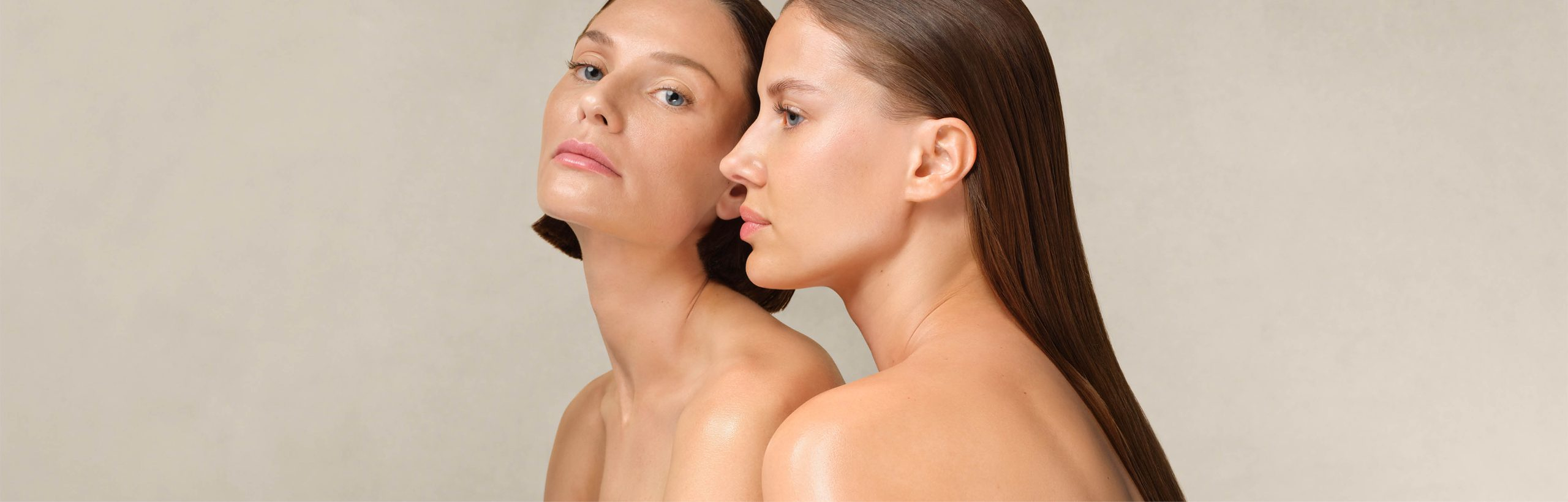 Zwei Frauen mit glatter Haut und zurückgekämmtem Haar, eine blickt frontal, die andere im Profil