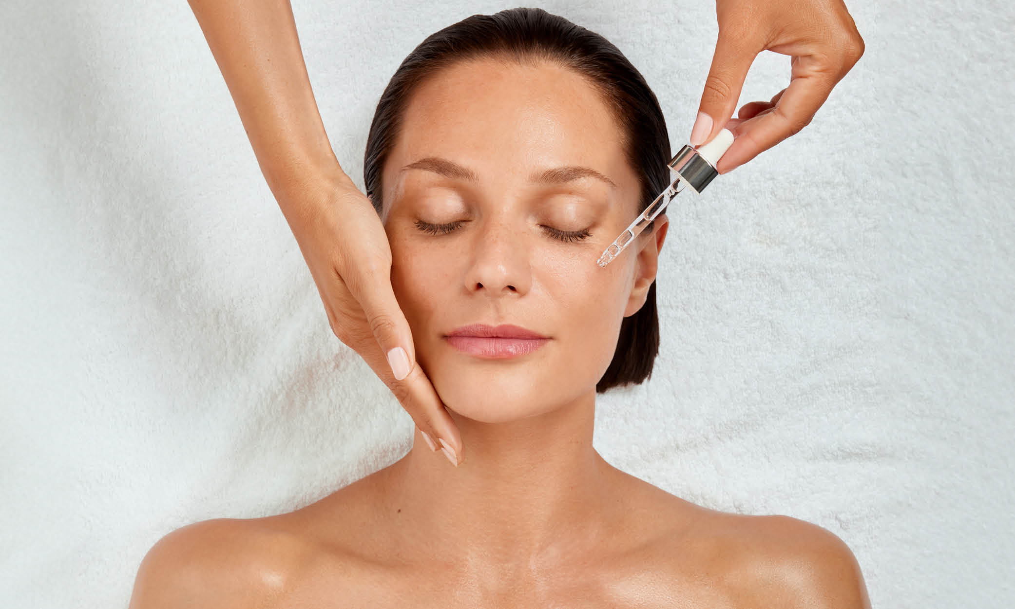 Frau mit geschlossenen Augen, Hand st&uuml;tzt die Wange, Pipette tr&auml;ufelt Serum aufs Gesicht