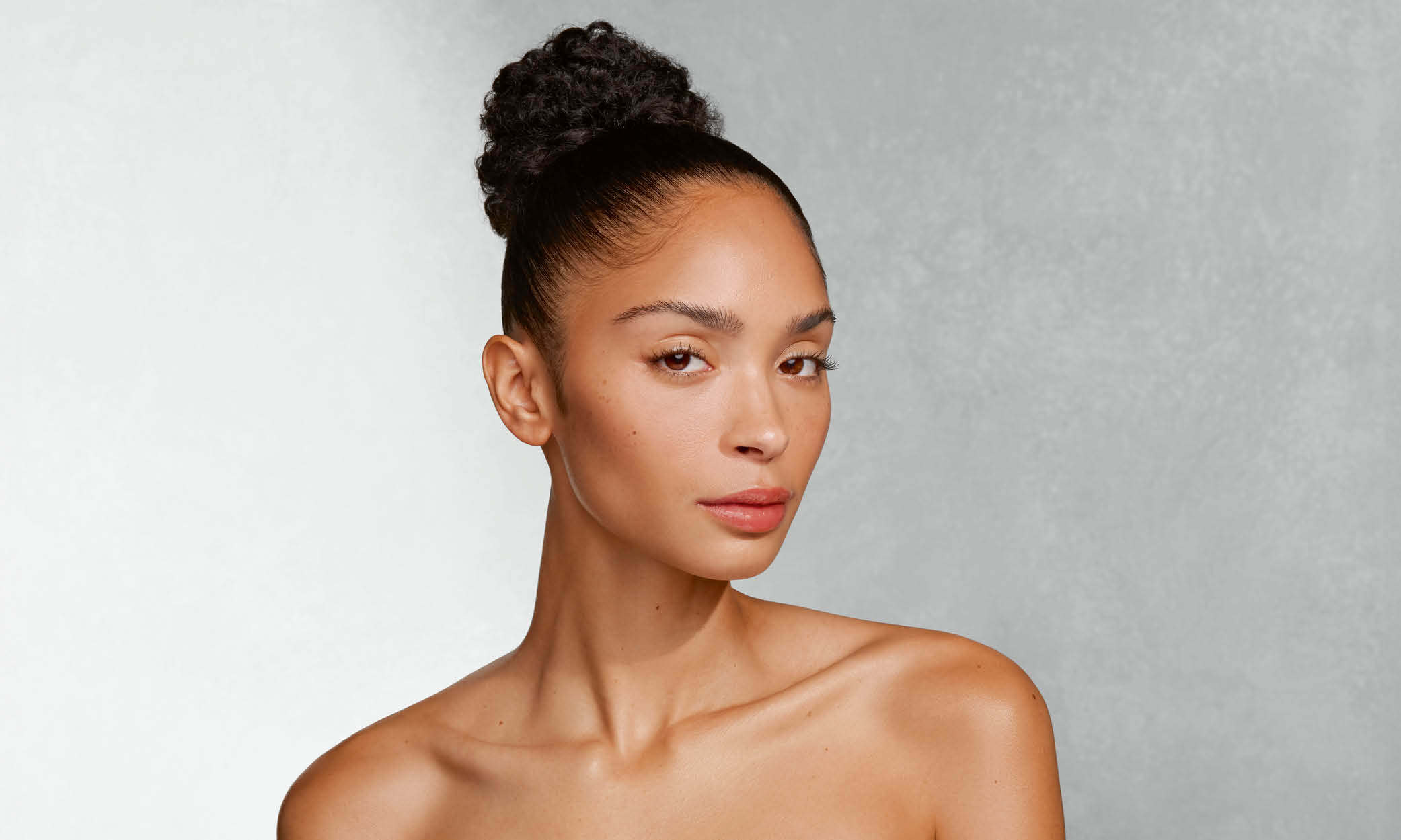 Frau mit hochgestecktem Haar und nackten Schultern blickt leicht gedreht