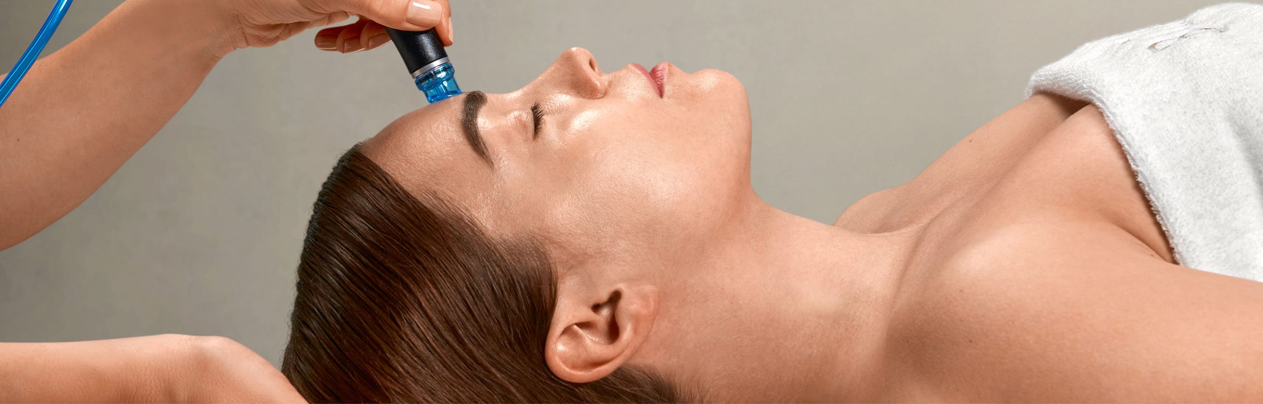 Frau liegt mit geschlossenen Augen erhält eine Hydrafacial-Behandlung