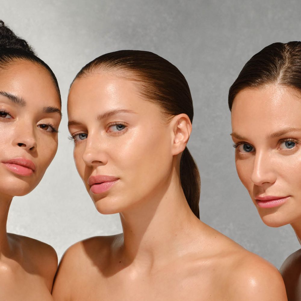 Drei Frauen Schulter an Schulter vor grauem Hintergrund